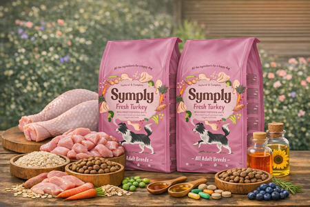 Two pink bags of 'Simply Fresh Turkey' dog food on a wooden table with pet treats and ingredients.