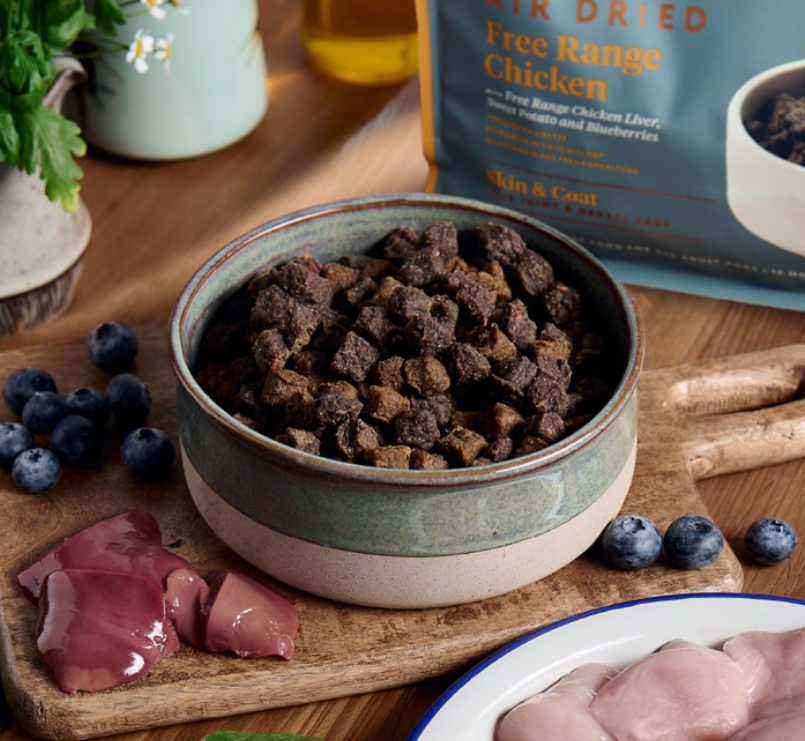 Bowl of McAdams Air Dried Chicken on a wooden surface with a package labeled 'Free Range Chicken' in the background