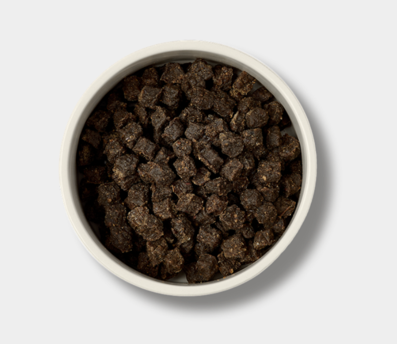 White bowl filled with dark brown pet food on a light gray background