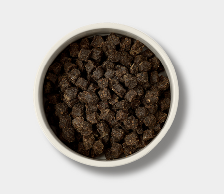 White bowl filled with dark brown pet food on a light gray background